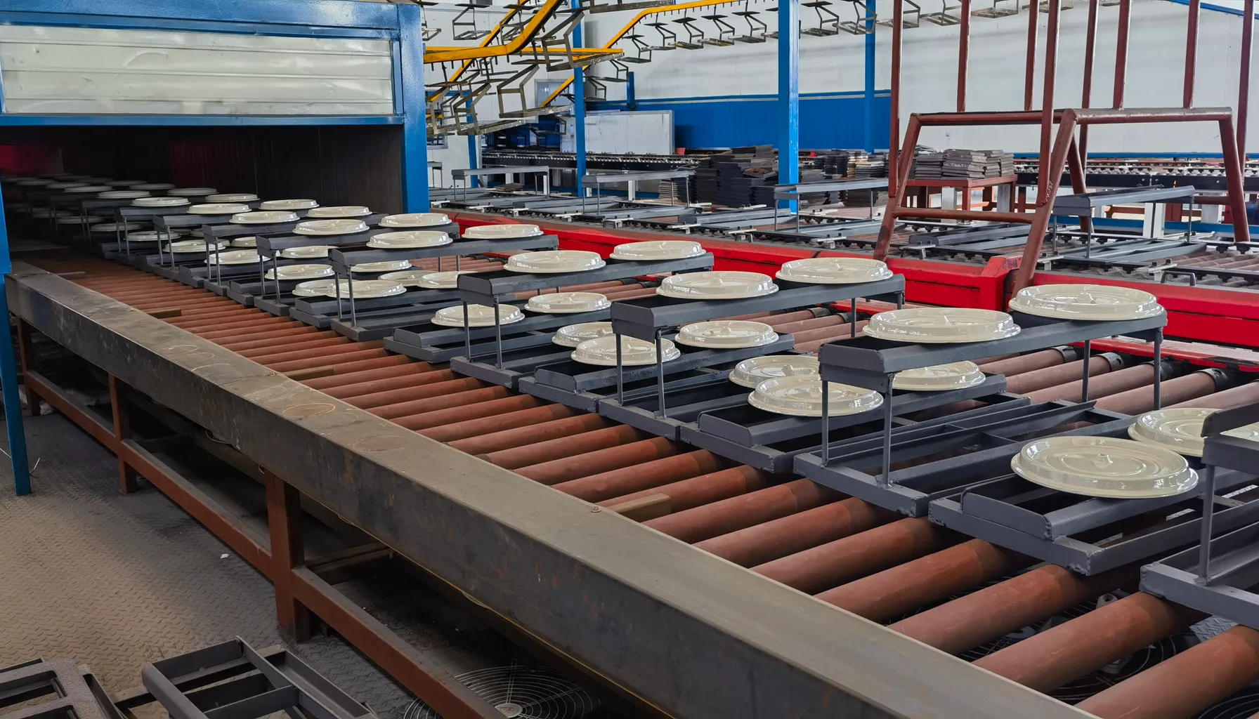 Enamel firing line — cookware lids on the conveyor into the kiln